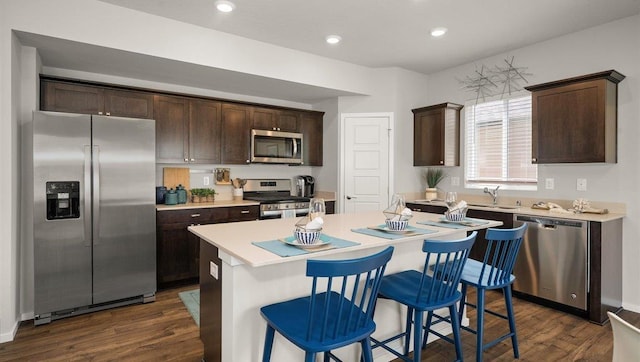 kitchen featuring stainless steel appliances, a center island, dark wood-type flooring, and dark brown cabinetry