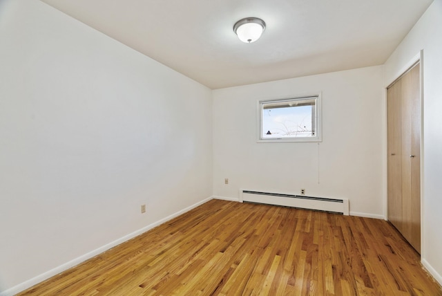 unfurnished bedroom with light wood-type flooring, baseboards, and baseboard heating