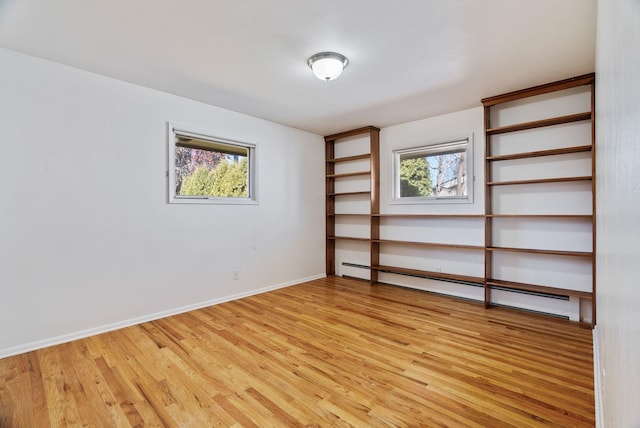 unfurnished room featuring baseboards, light wood finished floors, and baseboard heating