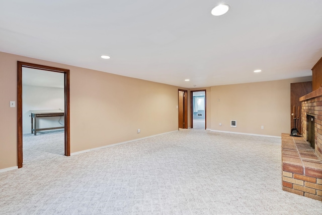 unfurnished living room with baseboards, recessed lighting, a fireplace, and light colored carpet