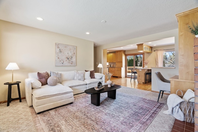 living area featuring light wood-style floors, baseboards, a textured ceiling, and recessed lighting