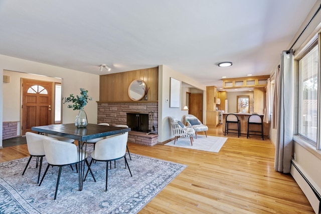 dining room featuring light wood-style floors, a fireplace, and baseboard heating