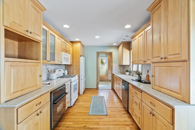 kitchen featuring white appliances, light brown cabinets, and a sink