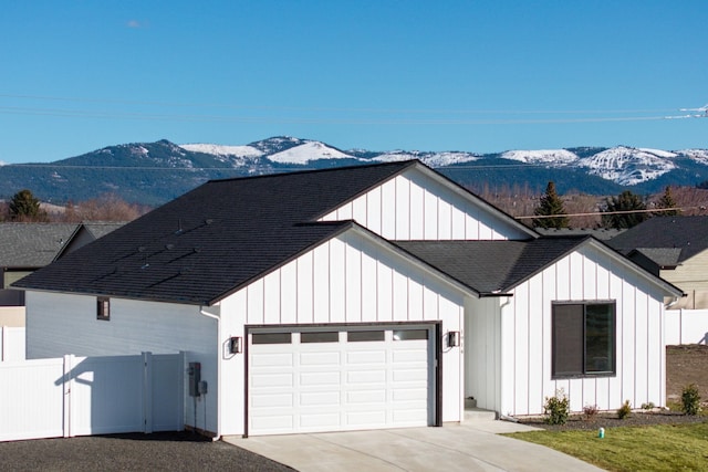 modern farmhouse featuring concrete driveway, board and batten siding, an attached garage, and a mountain view