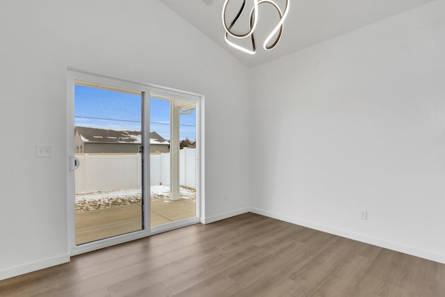 unfurnished room with lofted ceiling, baseboards, and wood finished floors