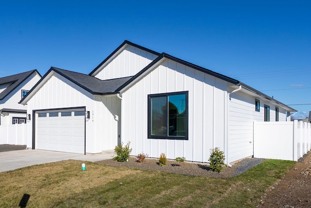 view of side of home with a garage, fence, concrete driveway, a yard, and roof with shingles