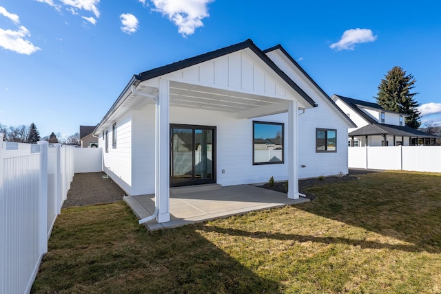 back of house featuring a yard, board and batten siding, a patio, and a fenced backyard