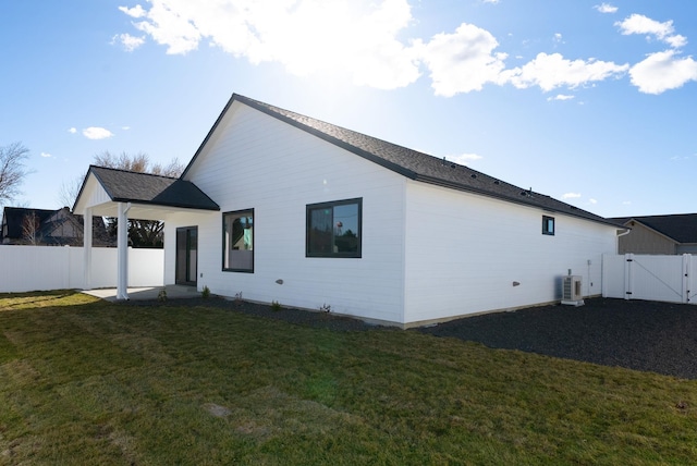 rear view of house featuring a gate, fence, and a lawn