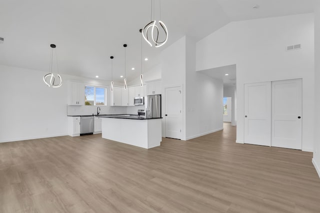 kitchen featuring stainless steel appliances, dark countertops, open floor plan, and visible vents