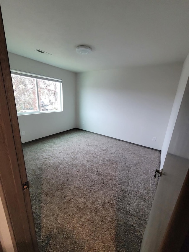 carpeted spare room featuring visible vents