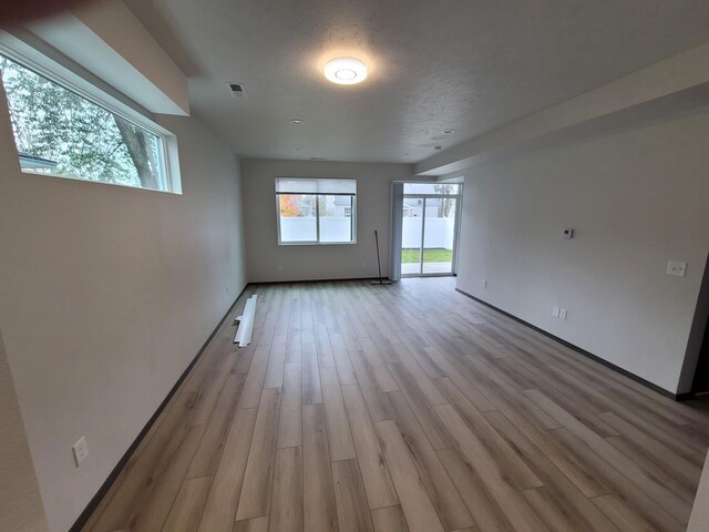 empty room featuring light wood-style floors, visible vents, and a textured ceiling