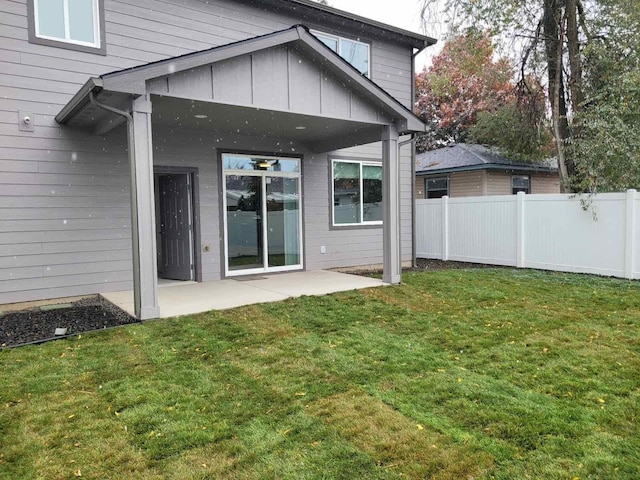 back of property featuring a lawn, a patio area, and fence