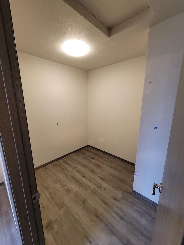 empty room featuring a textured ceiling, baseboards, and wood finished floors