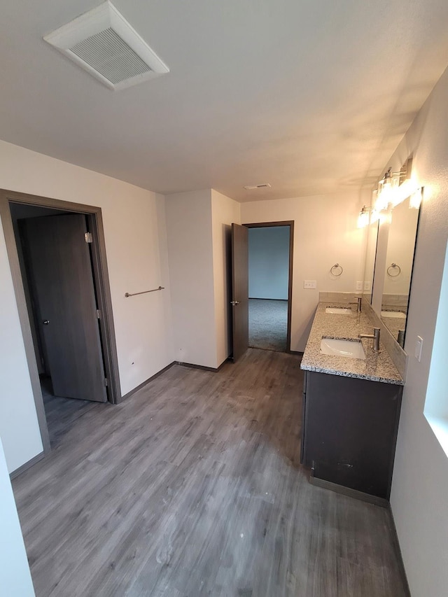 bathroom featuring double vanity, wood finished floors, a sink, and visible vents