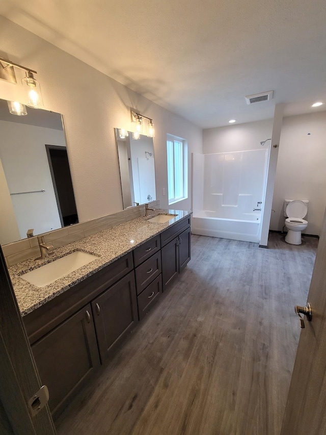 bathroom with toilet, wood finished floors, a sink, and visible vents