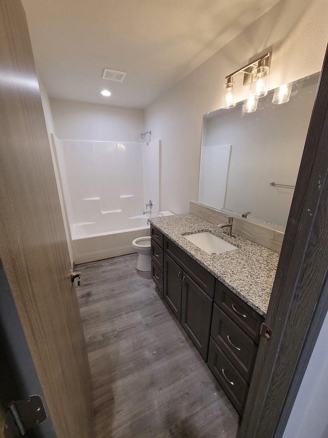 full bathroom featuring shower / bath combination, visible vents, toilet, wood finished floors, and vanity