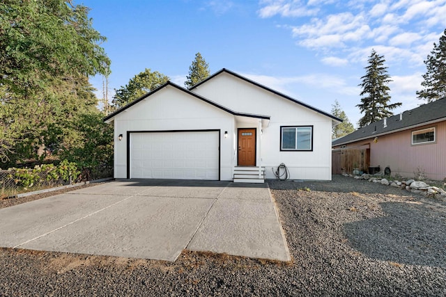 view of front facade with a garage, concrete driveway, and fence