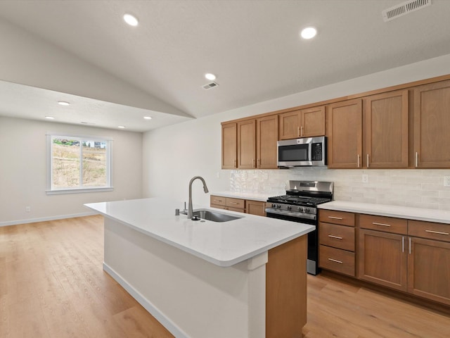 1624 S Moen St Unit 3/1Orchard, Spokane Valley, WA 99016 - kitchen featuring appliances with stainless steel finishes, brown cabinetry, backsplash, vaulted ceiling, and light wood-type flooring
