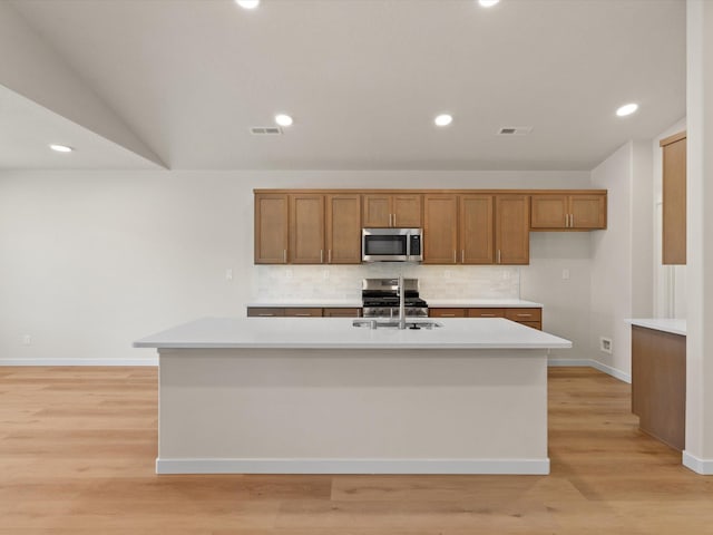 1624 S Moen St Unit 3/1Orchard, Spokane Valley, WA 99016 - kitchen featuring stainless steel appliances, brown cabinets, backsplash, light countertops, and a kitchen island with sink