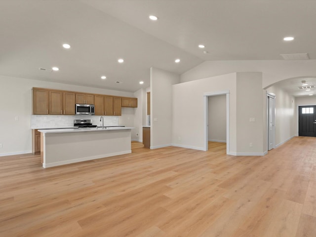 1624 S Moen St Unit 3/1Orchard, Spokane Valley, WA 99016 - kitchen featuring appliances with stainless steel finishes, arched walkways, an island with sink, vaulted ceiling, and brown cabinets