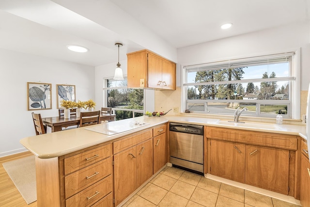 kitchen featuring white stovetop, a peninsula, a sink, light countertops, and stainless steel dishwasher