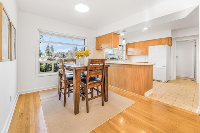 dining space with light wood-style flooring and baseboards