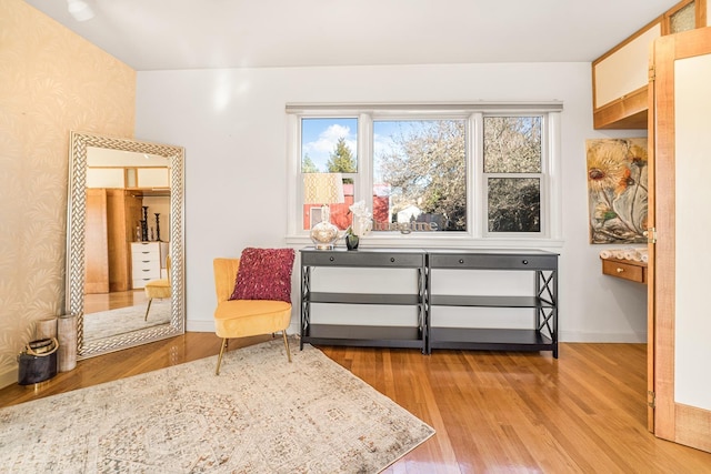 living area featuring light wood-style flooring, baseboards, and wallpapered walls