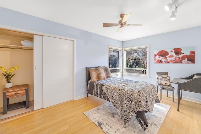 bedroom with a ceiling fan, light wood-style flooring, baseboards, and a closet