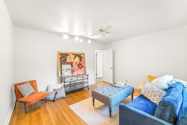 living room featuring light wood-style floors, baseboards, and a ceiling fan