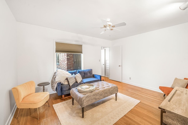 living area with a ceiling fan, baseboards, and light wood finished floors