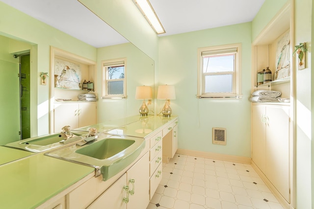 bathroom with baseboards, heating unit, vanity, and tile patterned floors