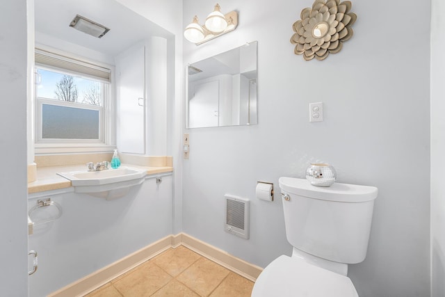 bathroom featuring heating unit, toilet, a sink, baseboards, and tile patterned floors