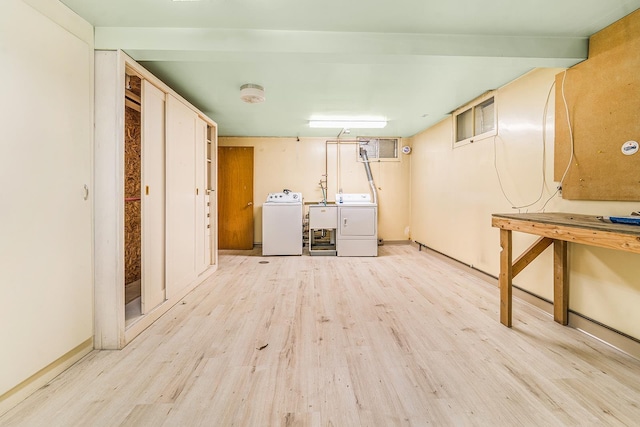 washroom with a sink, light wood finished floors, laundry area, and washer and dryer