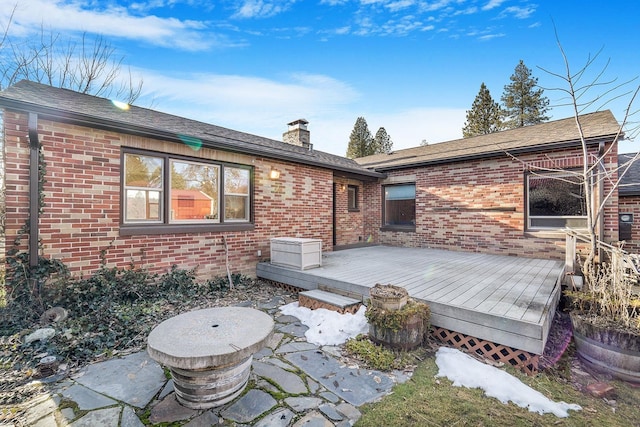 rear view of house featuring a chimney, a deck, and brick siding