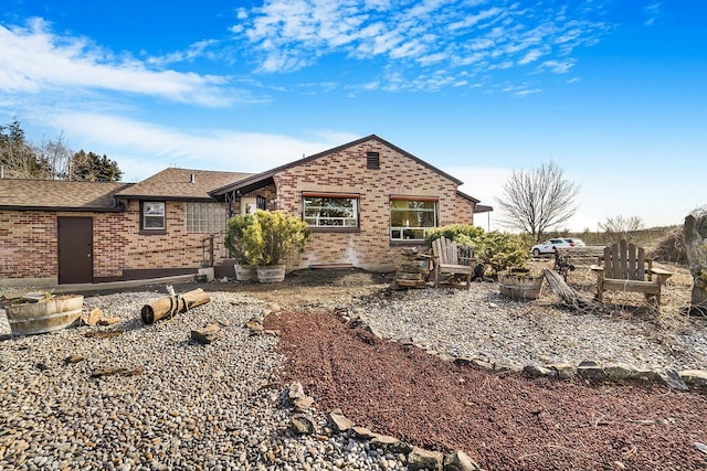 rear view of property featuring brick siding and a shingled roof