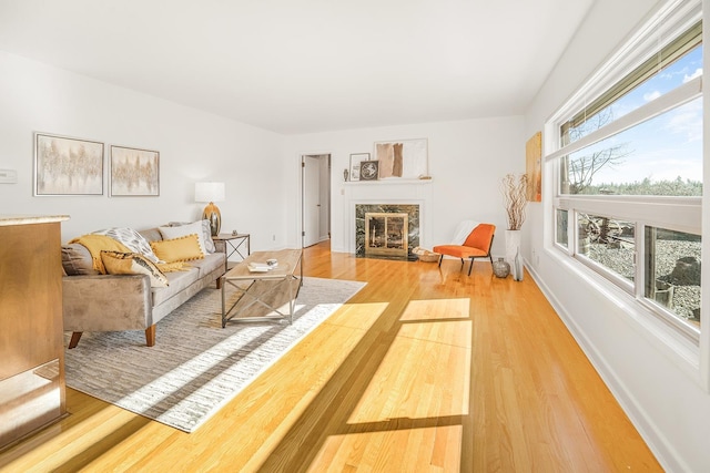 living room featuring light wood-style floors, baseboards, and a premium fireplace