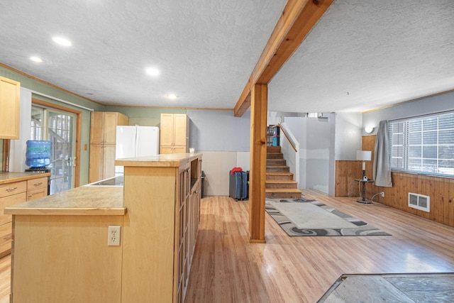 kitchen with a center island, visible vents, light brown cabinetry, wainscoting, and light wood-type flooring