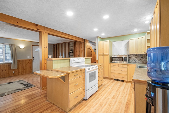 kitchen featuring white electric stove, stainless steel microwave, light brown cabinetry, light wood-type flooring, and a peninsula