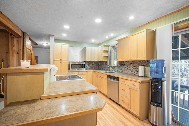 kitchen with light wood finished floors, appliances with stainless steel finishes, light brown cabinets, and tasteful backsplash