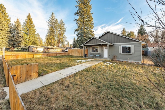 view of front facade with fence, a front lawn, and board and batten siding