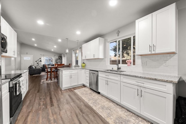 kitchen with lofted ceiling, stainless steel appliances, wood finished floors, a sink, and white cabinetry