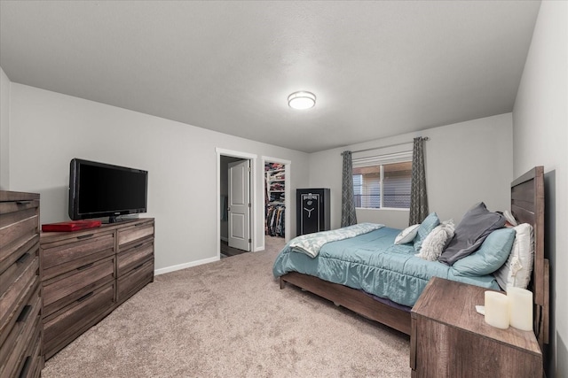 carpeted bedroom with a walk in closet and baseboards