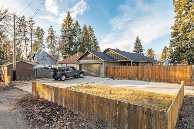 view of front of property with driveway, a fenced front yard, board and batten siding, and an attached garage