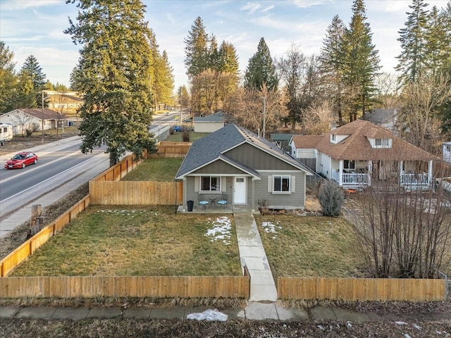 view of front of house featuring a front lawn, a shingled roof, and fence private yard