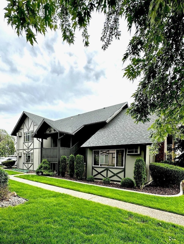 view of front of home featuring a shingled roof, a front yard, and stucco siding