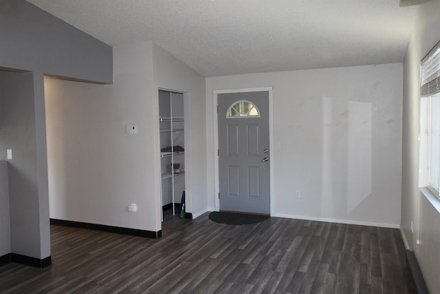 entrance foyer featuring vaulted ceiling, dark wood-style flooring, and baseboards