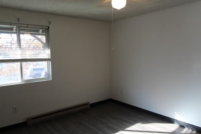 empty room with dark wood finished floors, a baseboard heating unit, ceiling fan, a textured ceiling, and baseboards