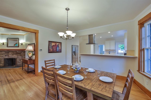 2508 S Grand Blvd, Spokane, WA 99203 - dining area featuring light wood-style floors, ornamental molding, a chandelier, a stone fireplace, and baseboards