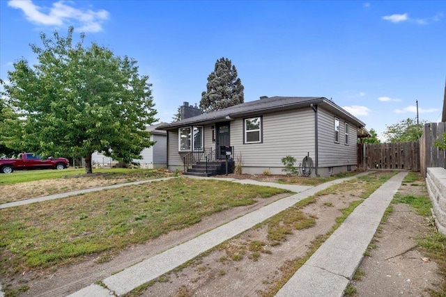 view of front of property featuring a chimney, fence, and a front lawn