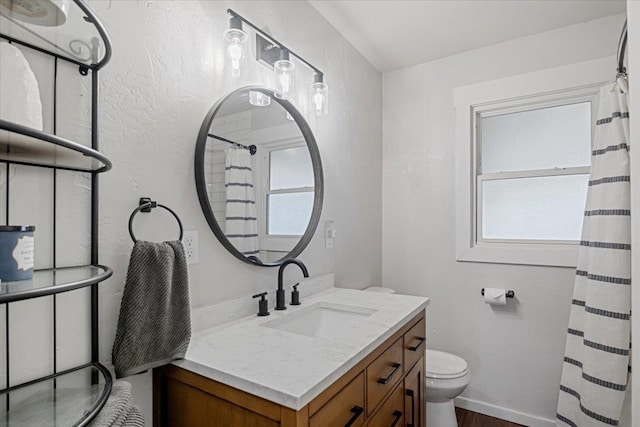 full bath with curtained shower, a healthy amount of sunlight, vanity, and toilet